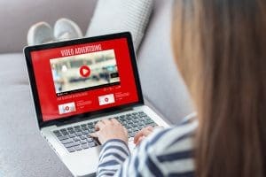 A woman engaged in video reviews, using a laptop.